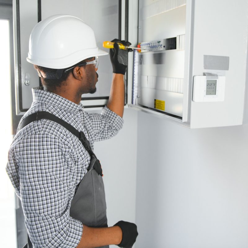 A male electrician works in a switchboard
