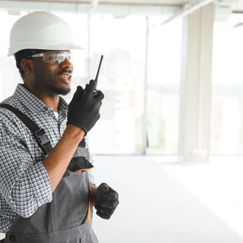 Builder in helmet is standing in front of the construction site