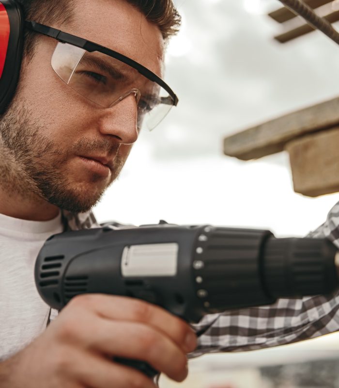 Builder working with drill on construction site
