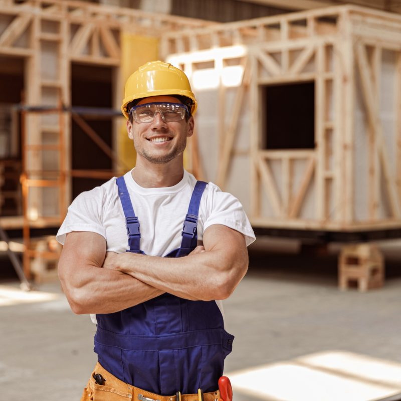 Cheerful young man builder standing at construction site