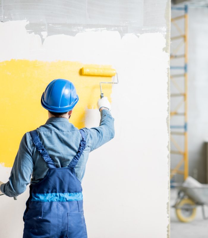 Workamn painting wall indoors