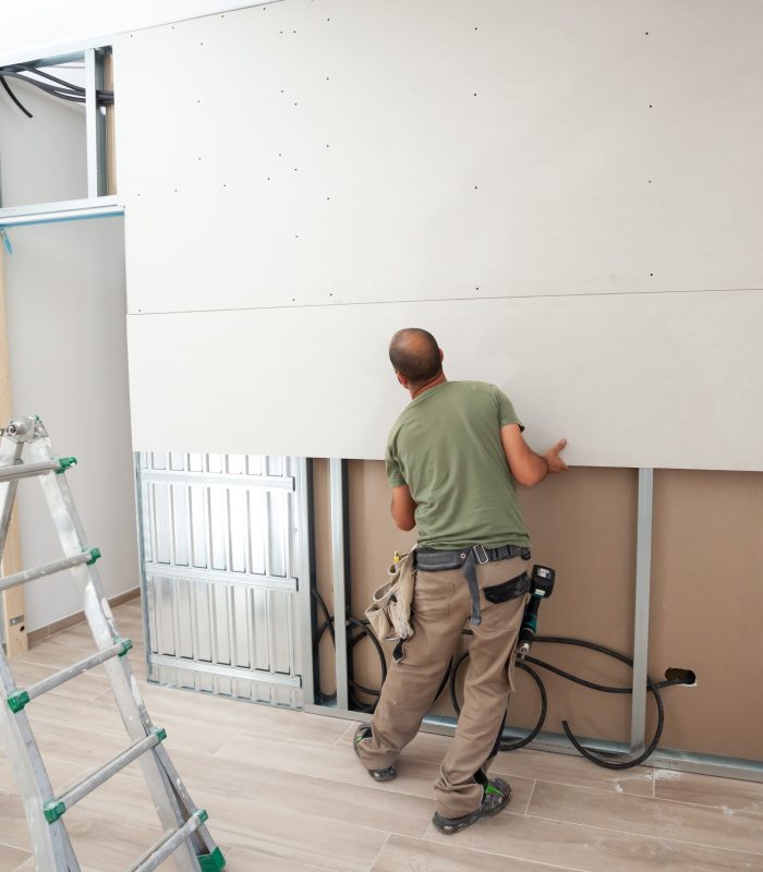 Worker building plasterboard wall.
